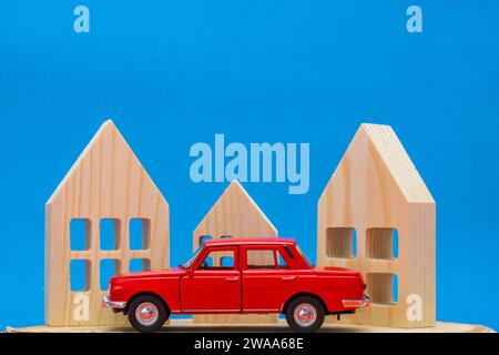 voiture jouet rouge avec des maisons en bois isolées sur bleu Banque D'Images