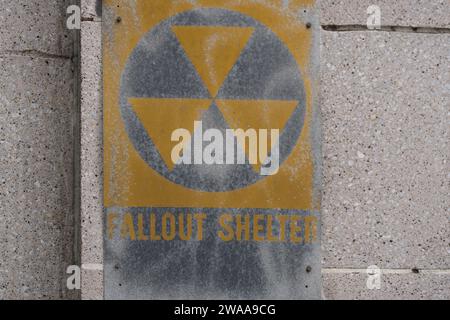 Ce panneau jaune foncé d'abri antichute sert de rappel des angoisses passées, gravées sur un mur de béton altéré, évoquant la contemplation historique. Banque D'Images