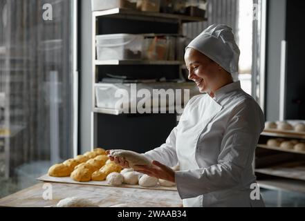 Femme expérimentée qualifiée boulanger formant des baguettes travaillant dans la boulangerie Banque D'Images