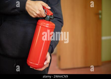 Un homme tient un extincteur dans le bureau. Le concept de sécurité incendie Banque D'Images