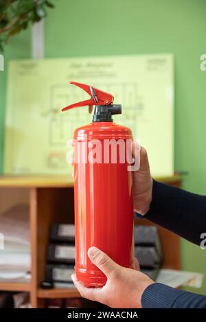 l'homme tient un extincteur dans ses mains sur le fond d'un plan d'évacuation en cas d'incendie. Le concept de sécurité incendie Banque D'Images