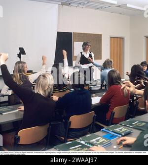 Dans les années 1970 Une classe scolaire est assise sur les bancs pendant une leçon avec une enseignante. Un rétroprojecteur se tient à l'avant, un dispositif commun dans les salles de classe à l'époque qui montrait la feuille transparente avec du texte et des images placées sur l'appareil sur l'écran. Les rétroprojecteurs étaient largement utilisés dans l'enseignement et les affaires avant l'avènement de la projection assistée par ordinateur. Suède années 1970 Banque D'Images