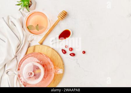 Théière en verre et tasse de thé aux baies bio avec miel - réglage de table esthétique. Espace de copie. Banque D'Images