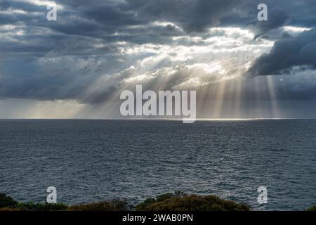 Lumière du soleil matinale brillante à travers le trou dans les nuages au-dessus de la mer à Maroubra Beach, Randwick, Sydney, Australie. Banque D'Images