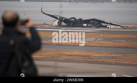 Tokyo, Japon. 03 janvier 2024. Un homme a pris des photos de l'Airbus A350 brûlé de Japan Airlines (JAL) après une collision avec un avion MA722 Mizunagi (Bombardier DHC-8-300) de la Garde côtière japonaise à l'aéroport international de Tokyo (aéroport Haneda) à Tokyo, Japon, le mercredi 3 janvier 2024. Photo de Keizo Mori/UPI crédit : UPI/Alamy Live News Banque D'Images