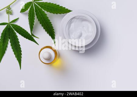 Récipient de crème de chanvre et d'huile de CBD vue de dessus sur fond blanc. Cosmétiques de soins corporels au cannabis avec feuille de marijuana. Banque D'Images