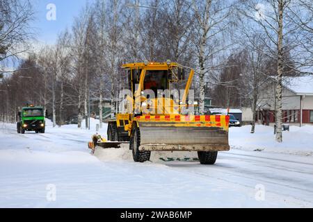 Niveleuse jaune Veekmas FG 2327 S enlevant la neige de la rue avec lame réglable, grinçant camion suit. Salo, Finlande. 27 décembre 2023. Banque D'Images