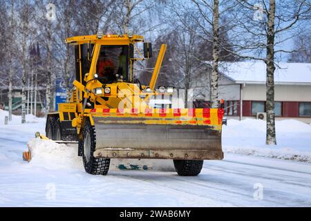 Niveleuse jaune Veekmas FG 2327 S enlevant la neige de la rue avec lame réglable après les chutes de neige hivernales. Salo, Finlande. 27 décembre 2023. Banque D'Images