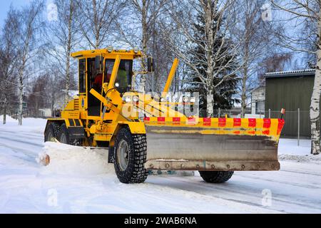 Niveleuse jaune Veekmas FG 2327 S enlevant la neige de la rue avec lame réglable après les chutes de neige hivernales. Salo, Finlande. 27 décembre 2023. Banque D'Images