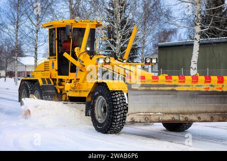 Niveleuse jaune Veekmas FG 2327 S enlevant la neige de la rue avec lame réglable après les chutes de neige hivernales. Salo, Finlande. 27 décembre 2023. Banque D'Images