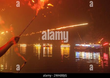 Les fêtards tirent des feux d'artifice sur la rivière Praek Tuek Chhu à minuit le soir du nouvel an de 2023 à 2024. Kampot, Cambodge. © Kraig Lieb Banque D'Images