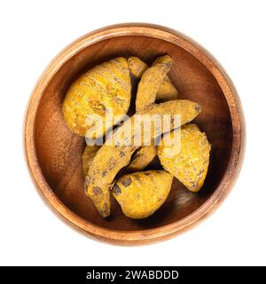 Racine de curcuma entière séchée dans un bol en bois. Rhizomes déshydratés de Curcuma longa, aussi appelés tumériques. Utilisé comme épice et comme colorant. Banque D'Images