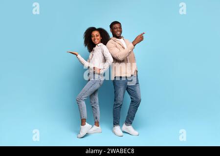 Heureux couple noir pointant latéralement à l'espace libre sur fond bleu Banque D'Images