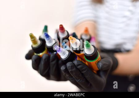 Femme maître de tatouage tenant des bouteilles d'encre colorée de tatouage. Concept d'art et de design. Gros plan Banque D'Images