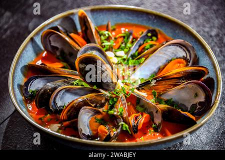 Une assiette de moules à la sauce tomate servie avec du persil et du citron Banque D'Images