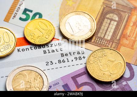 3 janvier 2024 : relevé de compte avec solde élevé entouré de billets et de pièces en euros *** Kontoauszug mit hohem Kontostand umgeben von Euro Geldscheinen und Münzen Banque D'Images