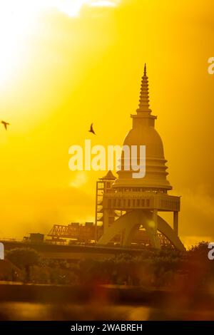 Le stupa est un monument de reliquaire bouddhiste qui est dit contenir un cheveu du Bouddha. Le soleil couchant jette une lueur chaude sur le stupa, et un oiseau est Banque D'Images