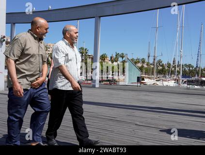 Barcelone, Espagne - 26 mai 2022 : deux frères marchent ensemble le long de la Rambla del Mar vers l'aquarium de Barcelone. Banque D'Images