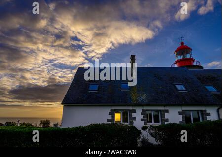 Phare avec un ciel de coucher de soleil brillant à travers une fenêtre du bâtiment Banque D'Images