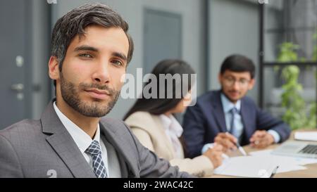 patron masculin dans le fond de ses collègues regarde la caméra dans un bureau moderne Banque D'Images