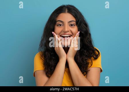 Portrait de jeune femme indienne émerveillée touchant son visage Banque D'Images