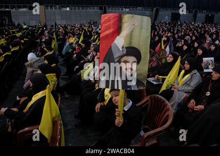 Beyrouth, Liban. 03 janvier 2024. Des partisans pro-iraniens du Hezbollah assistent à une messe alors que le secrétaire général du Hezbollah Hassan Nasrallah semble prononcer un discours télévisé pour marquer le 4e anniversaire de l'assassinat d'Abu Mahdi al-Mohandes, le chef adjoint de la milice irakienne Hashd al-Shaabi, et le commandant de la Force Qods iranienne Qasem Soleiman par un drone américain en Irak en 2020. Crédit : Marwan Naamnai/dpa/Alamy Live News Banque D'Images