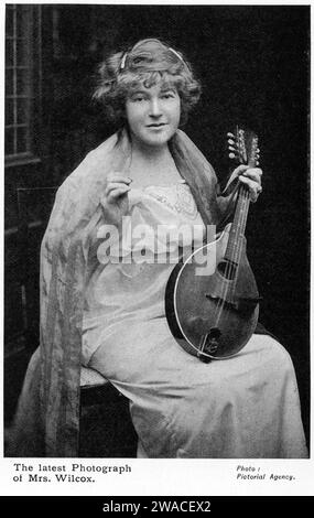 Portrait en demi-teinte de la poète Ella Wheeler Wilcox avec sa mandoline, vers 1913. Ella (1850 – 1919) est une auteure et poétesse américaine. Ses œuvres comprennent la collection Poems of passion et le poème Solitude, qui contient les lignes « Laugh, and the World rit with you ; pleurez, et vous pleurez seul ». Banque D'Images