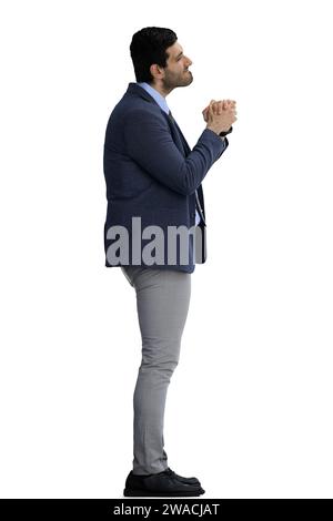 Un homme dans un costume de bureau sur un fond blanc plie ses mains et supplie, de profil Banque D'Images