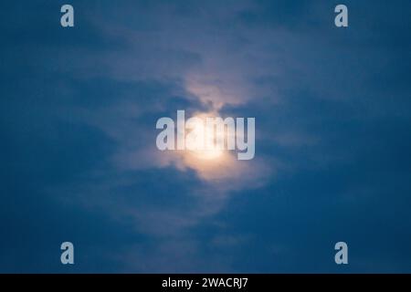 La pleine lune se lève derrière des nuages colorés à Woodland, CA, USA en décembre 2023. Banque D'Images