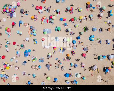 Vue aérienne de haut en bas des gens se relaxant à la plage par une journée ensoleillée à Costa da Caparica près de Lisbonne, Portugal. Banque D'Images