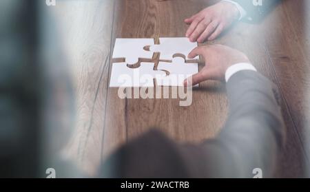 Groupe de gens d'affaires qui mettent un puzzle sur une table Banque D'Images