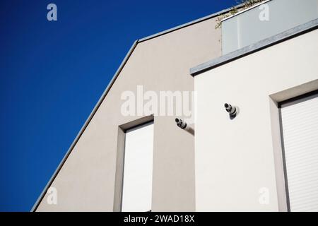 Façade de bâtiment moderne aux lignes épurées, contrastant avec un ciel bleu clair, avec des cheminées à gaz et des volets fermés Banque D'Images