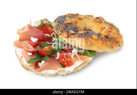 Bagel savoureux avec jambon séché, roquette, fromage à la crème et tomates isolé sur blanc Banque D'Images