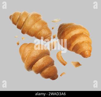 Délicieux croissants frais tombant sur fond gris Banque D'Images