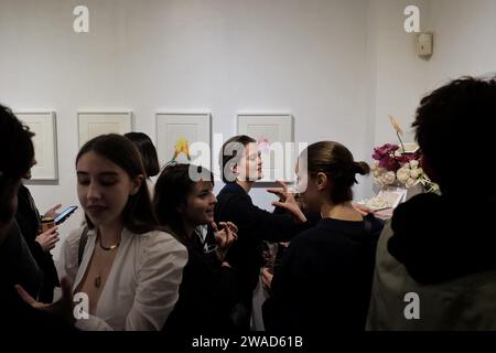 Jeunes femmes à la mode en conversation dans une salle blanche lors d'une ouverture d'art dans une galerie d'art contemporain à la mode à la périphérie de la ville Banque D'Images