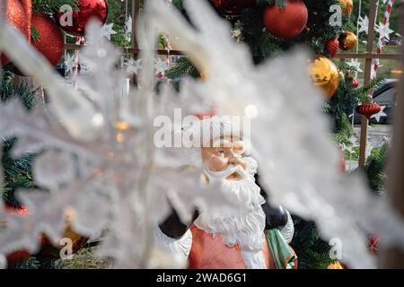 Statue de Santa Clause à côté des arbres de Noël et des flocons de neige en plastique Banque D'Images