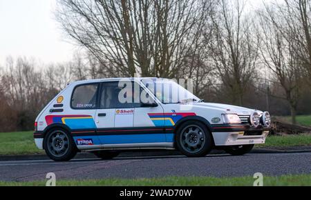 Stony Stratford, Royaume-Uni 1 janvier 2024. Voiture blanche Peugeot 205 à hayon 1990 arrivant à Stony Stratford pour le New Year Day vintage et classique ve Banque D'Images