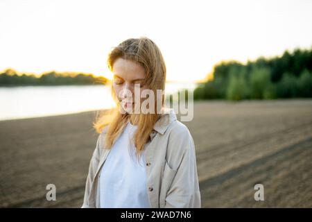Portrait de femme debout sur la plage au coucher du soleil Banque D'Images