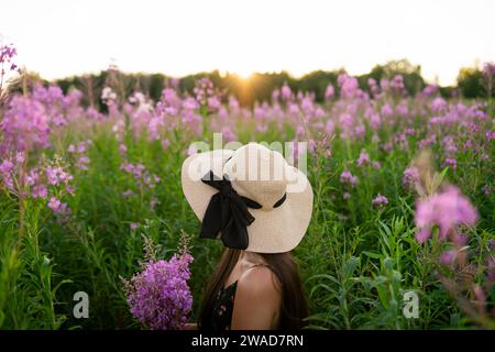Vue latérale de la jeune femme regardant des fleurs sur le pré Banque D'Images