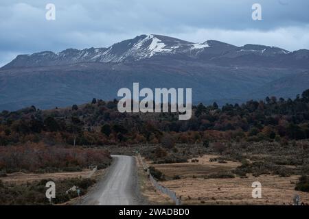 chemin de terre dans la campagne menant à une montagne enneigée Banque D'Images