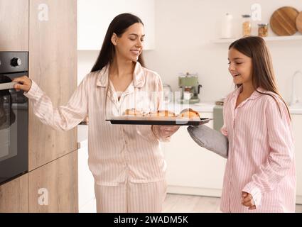 Mère heureuse avec sa petite fille et petits pains savoureux dans la cuisine Banque D'Images