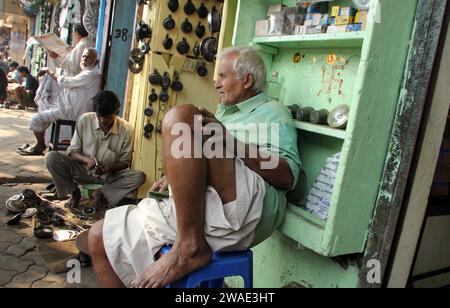 Homme indien devant un magasin vendant des pièces de voiture sur Mallik bazar à Kolkata, en Inde Banque D'Images