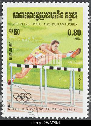 Timbre-poste annulé imprimé par le Cambodge, qui montre la course de haies, la promotion des Jeux olympiques d'été à Los Angeles, vers 1984. Banque D'Images
