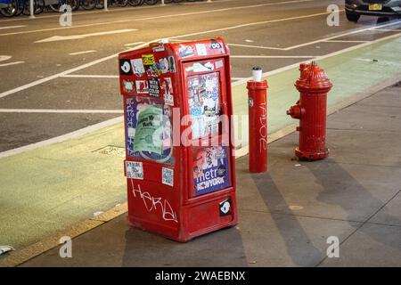 Un distributeur automatique de journaux rouge et une bouche d'incendie dans une rue de New York Banque D'Images