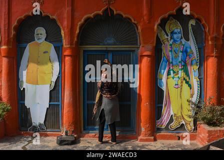 Ayodhya, Inde. 26 décembre 2023. Nilam Singh, une résidente de RAM Janmabhoomi Path, réagit à la caméra en ouvrant la porte du temple où les découpes du Premier ministre indien Narendra Modi et du seigneur hindou RAM peuvent être vues à Ayodhya. Ayodhya est une ville ancienne dans le nord de l'Inde qui a une grande importance religieuse et historique dans l'hindouisme, car elle est considérée comme le lieu de naissance du Seigneur Rama, une divinité vénérée dans la mythologie hindoue. En novembre 2019, la Cour suprême de l'Inde a rendu un jugement historique en faveur de la construction d'un temple hindou sur le site controversé d'Ayodhya. (Crédit Banque D'Images