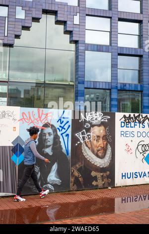 Homme marchant passant devant des peintures murales lors de la nouvelle construction d'un bâtiment multifonctionnel appelé « huis van Delft » aux couleurs de delftware dans le centre-ville de Delft Banque D'Images