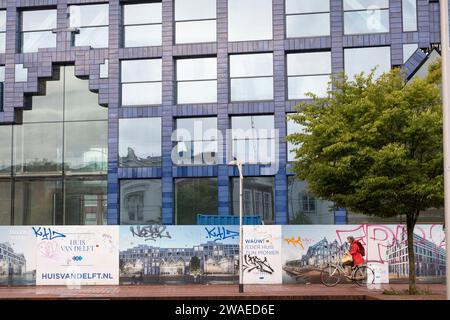 Cycliste passant une nouvelle construction de bâtiment multifonctionnel appelé 'huis van Delftt' aux couleurs de delftware dans le centre-ville de Delft Banque D'Images