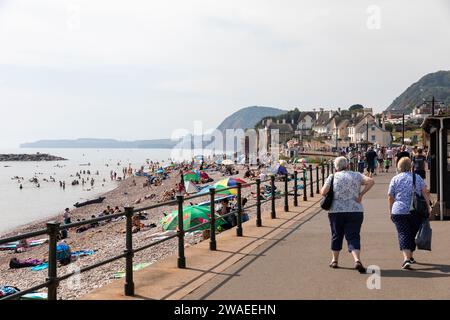 Sidmouth Devon, Angleterre, deux femmes âgées marchant le long de l'esplanade Sidmouth pendant que les gens se détendent sur la plage, chaud jour de septembre 2023, Royaume-Uni Banque D'Images