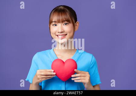 Femme asiatique avec coeur rouge sur fond violet Banque D'Images