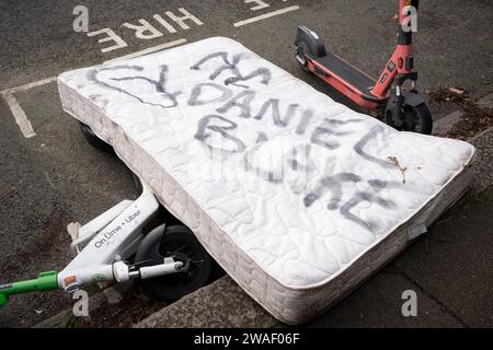 Un matelas qui a été jeté sur le trottoir à Herne Hill a le nom Daniel Blake pulvérisé sur le dessus, le 3 janvier 2024, à Londres, Angleterre. I, Daniel Blake est un film dramatique britannique de 2016 écrit par Paul Laverty et réalisé par Ken Loach qui décrit un homme d'âge moyen qui se voit refuser une allocation d'emploi et de soutien bien qu'il ait été déclaré inapte au travail par son médecin. Plus largement, il s'agissait d'une critique des politiques injustes du gouvernement conservateur en matière de travail et de bien-être social. Banque D'Images